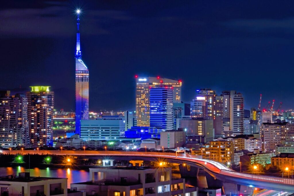 Illuminated Fukuoka Tower at night with city skyline and waterfront views
