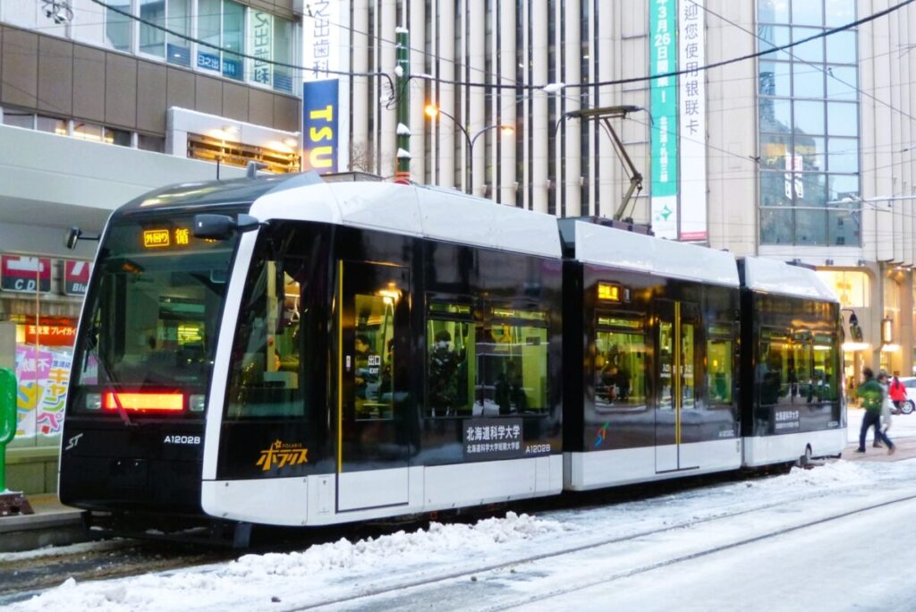 Sapporo streetcar running through snowy streets in winter