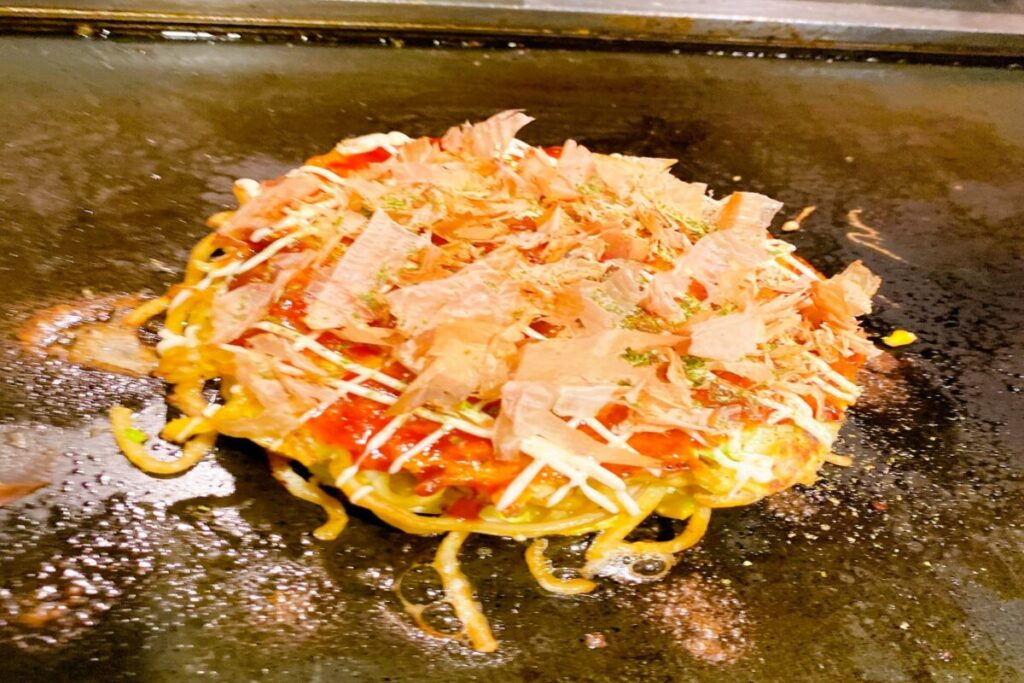 Modern yaki Japanese savory pancake with noodles, Osaka style okonomiyaki variation